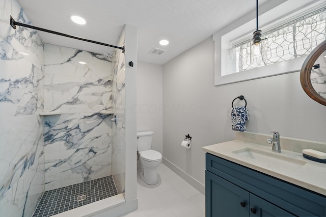 bathroom featuring a tile shower, vanity, toilet, and tile patterned floors