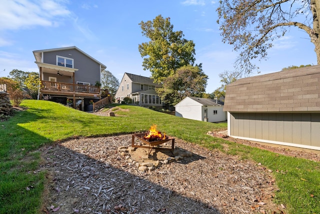 view of yard with a storage shed, a deck, and an outdoor fire pit