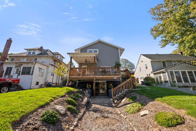 back of property with a lawn, a wooden deck, and ceiling fan