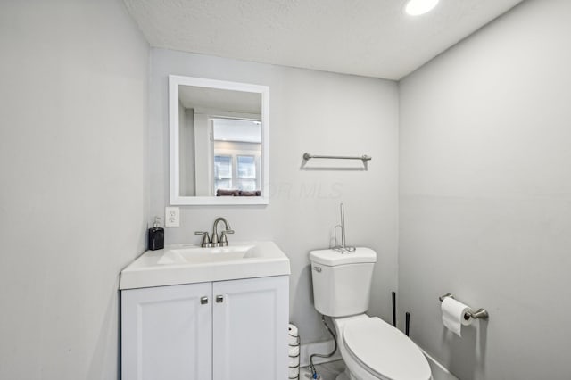 bathroom featuring vanity, a textured ceiling, and toilet