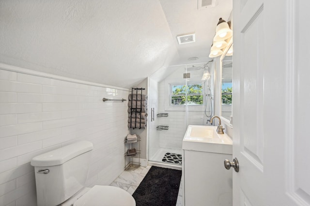 bathroom featuring vanity, lofted ceiling, toilet, tiled shower, and a textured ceiling