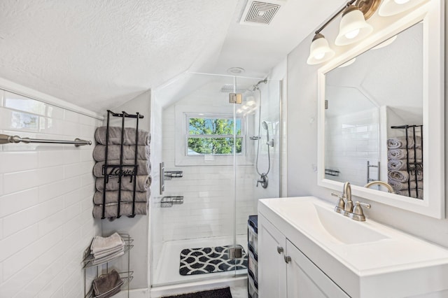 bathroom with vanity, a shower with door, a textured ceiling, and vaulted ceiling