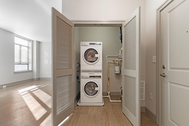 laundry room featuring light hardwood / wood-style floors and stacked washer / dryer