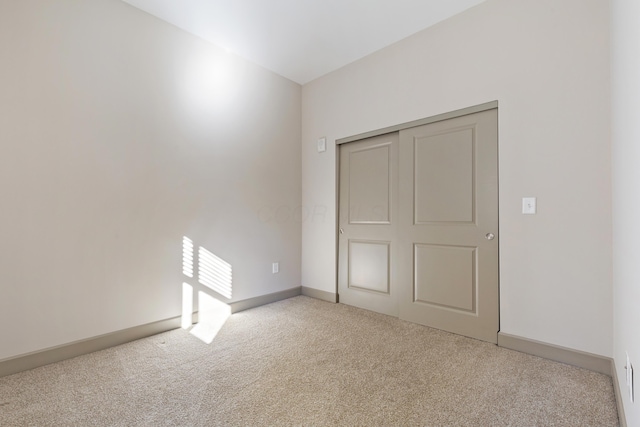 unfurnished bedroom featuring light colored carpet and a closet