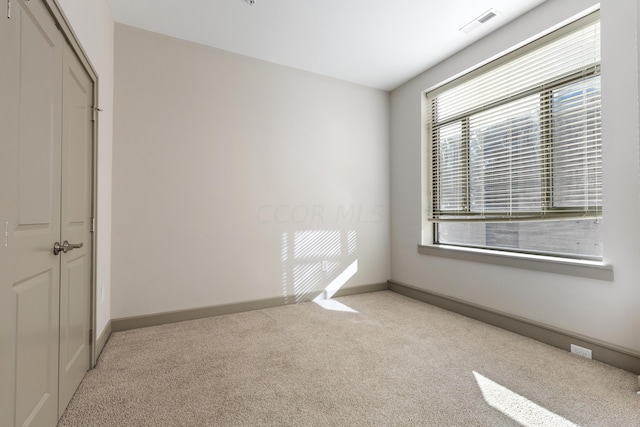 unfurnished bedroom with a closet, light colored carpet, and multiple windows