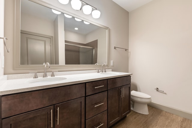 bathroom featuring hardwood / wood-style flooring, vanity, toilet, and a shower with shower door