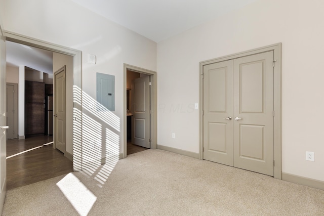 unfurnished bedroom with carpet flooring, electric panel, and a closet