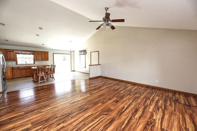 unfurnished living room with dark wood-style floors, a sink, vaulted ceiling, baseboards, and ceiling fan