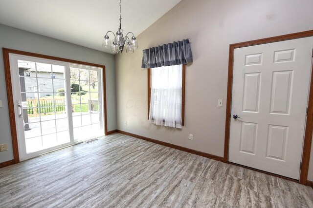 interior space featuring baseboards, visible vents, a chandelier, lofted ceiling, and wood finished floors
