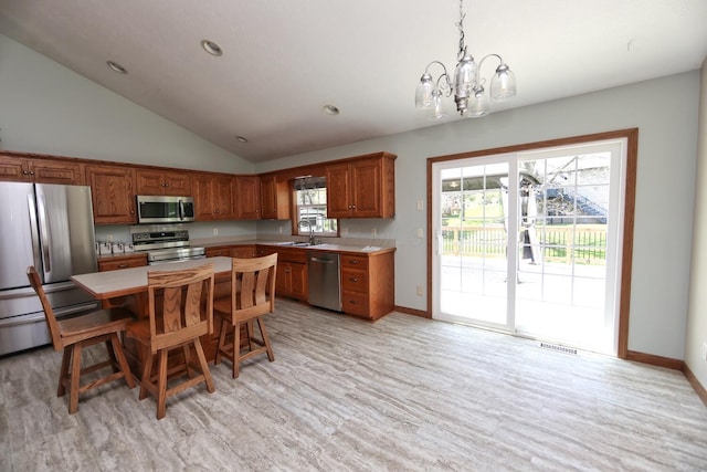 kitchen featuring vaulted ceiling, brown cabinets, a chandelier, stainless steel appliances, and light countertops