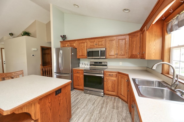 kitchen featuring light wood finished floors, stainless steel appliances, a sink, light countertops, and high vaulted ceiling