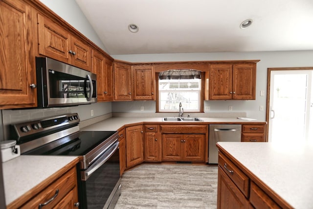 kitchen featuring stainless steel appliances, a sink, and brown cabinetry