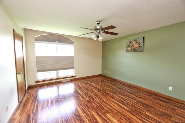 unfurnished room with wood finished floors, baseboards, a ceiling fan, and visible vents