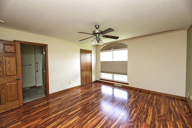unfurnished room with wood finished floors, visible vents, a ceiling fan, and baseboards