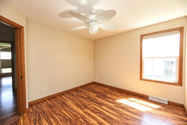 unfurnished room with dark wood-type flooring, plenty of natural light, visible vents, and baseboards