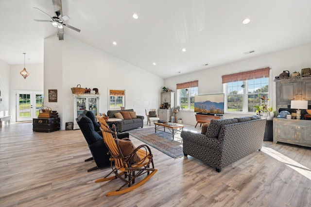 living room featuring ceiling fan, light hardwood / wood-style floors, high vaulted ceiling, and french doors