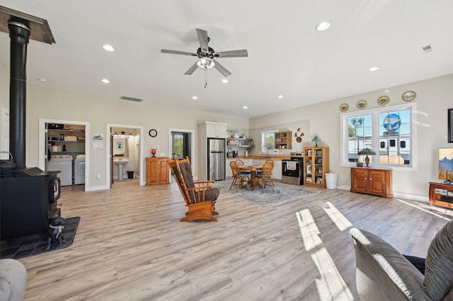 living room with washer and clothes dryer, a wood stove, plenty of natural light, and light hardwood / wood-style floors