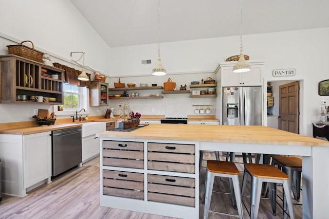 kitchen with white cabinets, wooden counters, and decorative light fixtures