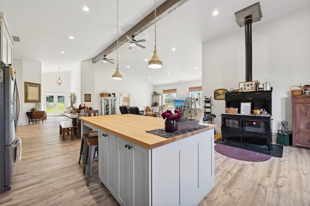 kitchen with white cabinets, beam ceiling, stainless steel fridge, and a healthy amount of sunlight