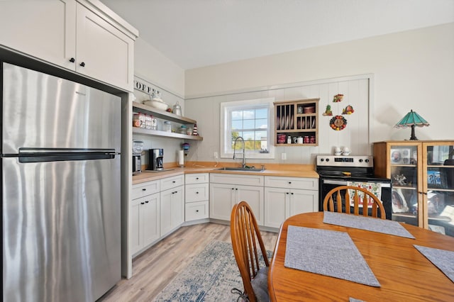 kitchen with sink, white cabinets, stainless steel appliances, and light wood-type flooring