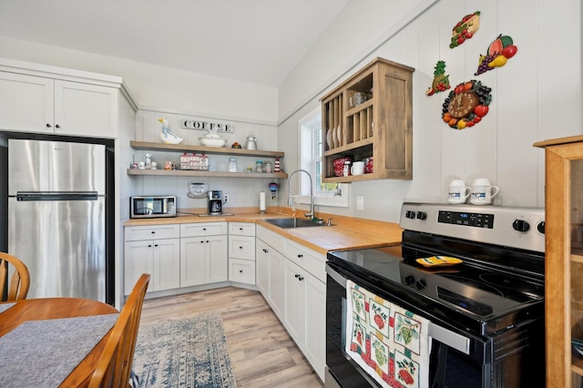 kitchen featuring appliances with stainless steel finishes, light hardwood / wood-style floors, white cabinetry, and sink