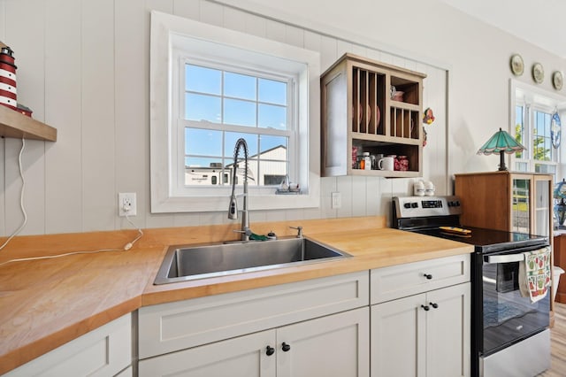 kitchen with white cabinets, sink, plenty of natural light, and electric stove