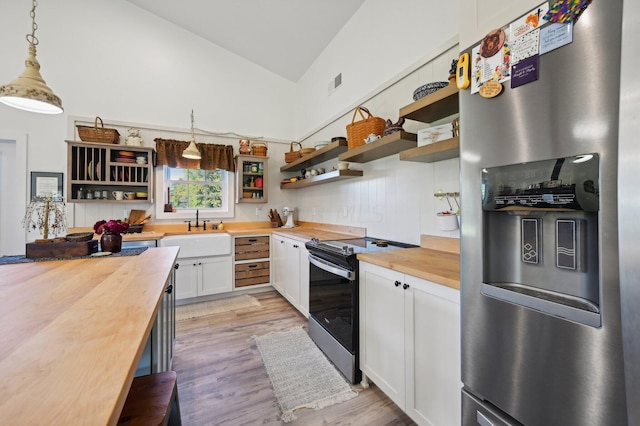 kitchen with butcher block countertops, decorative light fixtures, range with electric stovetop, and stainless steel refrigerator with ice dispenser