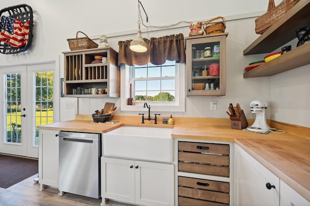 kitchen featuring white cabinetry, hanging light fixtures, stainless steel dishwasher, and wood counters