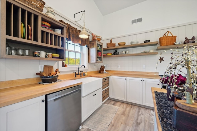 kitchen featuring wooden counters, stainless steel dishwasher, sink, white cabinetry, and hanging light fixtures