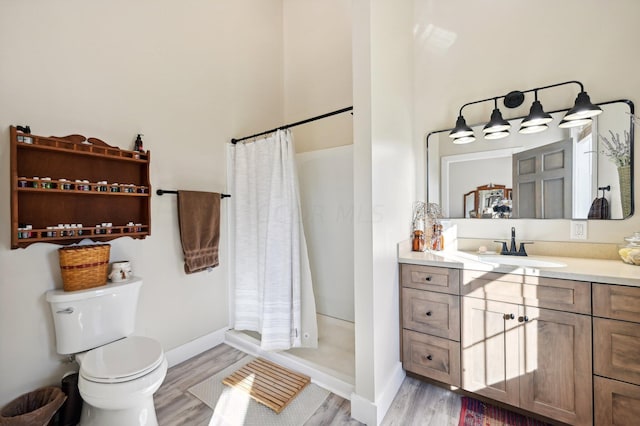 bathroom featuring hardwood / wood-style flooring, toilet, vanity, and walk in shower