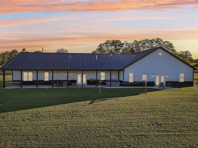 back house at dusk featuring a yard and a patio