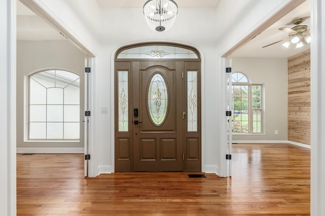 entrance foyer with ceiling fan with notable chandelier and wood-type flooring