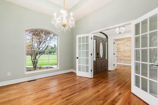 unfurnished dining area featuring french doors, wood-type flooring, and a notable chandelier