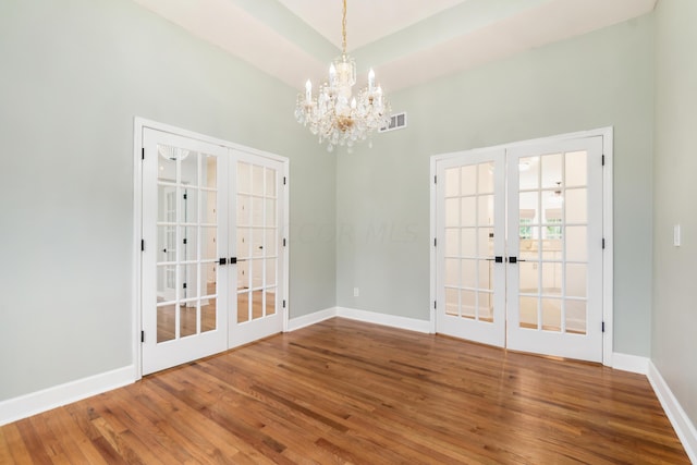 unfurnished room featuring french doors, an inviting chandelier, and hardwood / wood-style floors