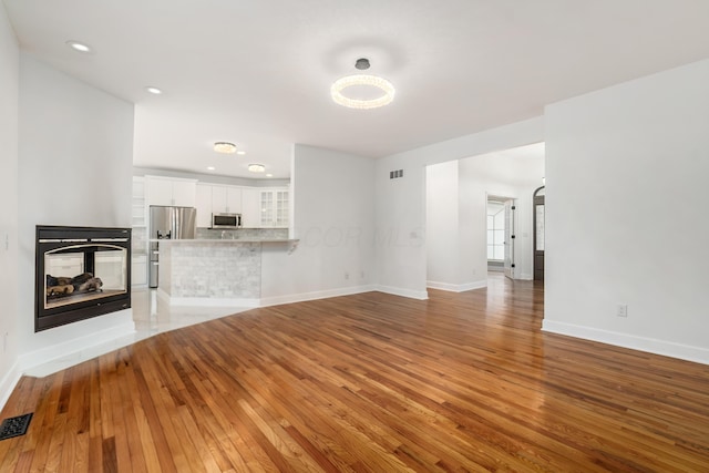 unfurnished living room with hardwood / wood-style flooring and a multi sided fireplace