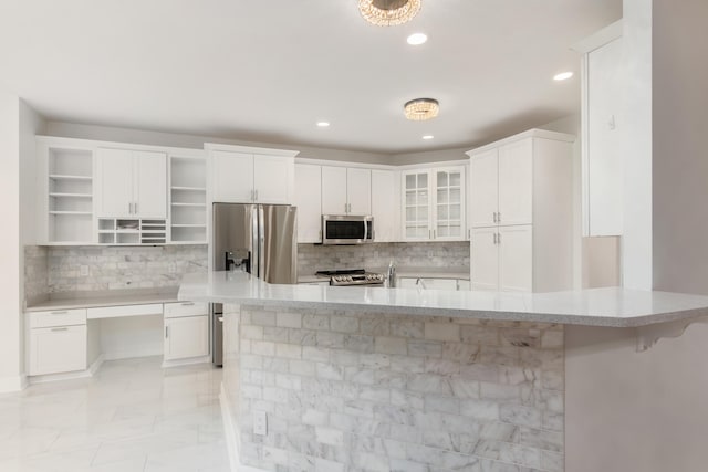 kitchen with backsplash, white cabinets, a breakfast bar area, and appliances with stainless steel finishes