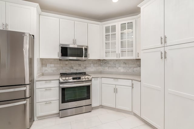 kitchen featuring decorative backsplash, light tile patterned floors, stainless steel appliances, and white cabinetry