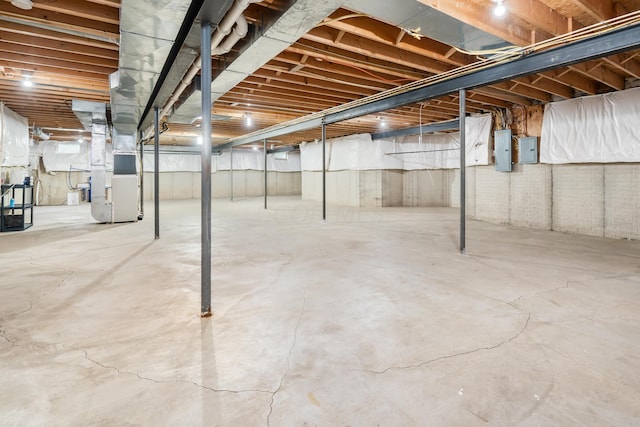 basement featuring electric panel and heating unit