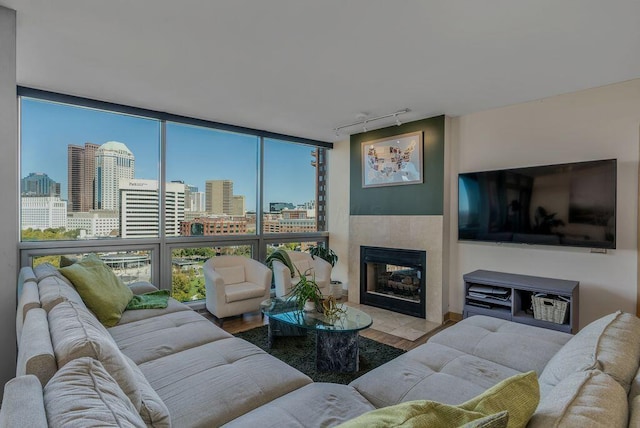 living room with hardwood / wood-style flooring, a wall of windows, a tile fireplace, and track lighting