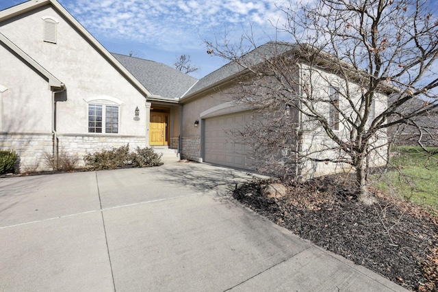 view of front of house with concrete driveway, stone siding, roof with shingles, an attached garage, and stucco siding