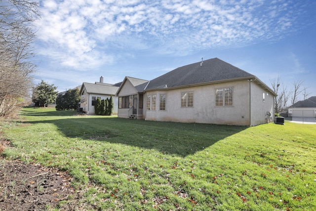 back of property featuring stucco siding, cooling unit, and a yard