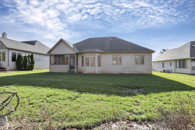 rear view of house featuring central air condition unit, a sunroom, a lawn, and stucco siding