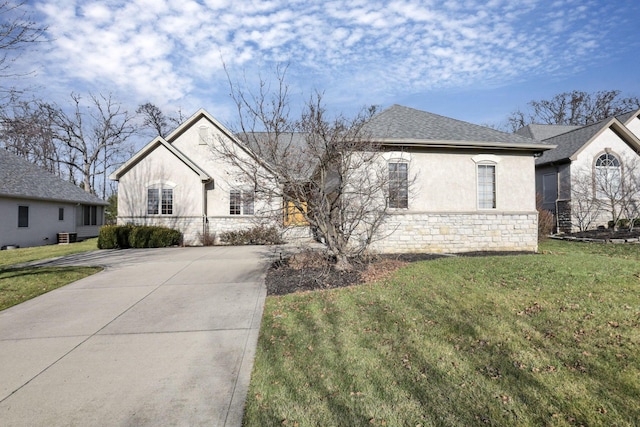 view of front facade featuring a shingled roof, concrete driveway, stone siding, a front lawn, and stucco siding