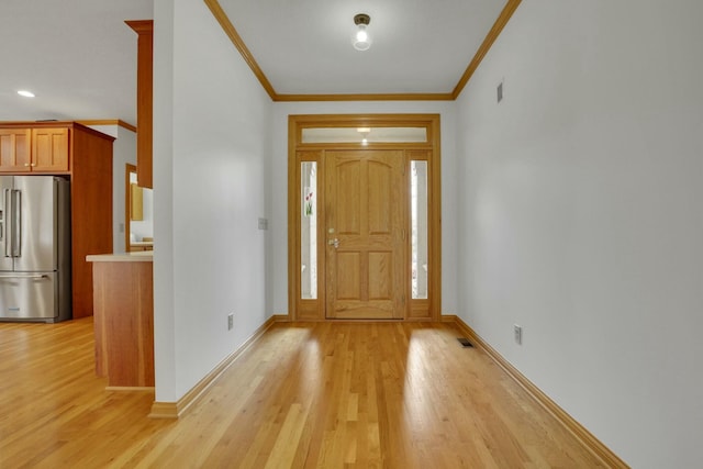 foyer entrance featuring ornamental molding, light wood-type flooring, and baseboards