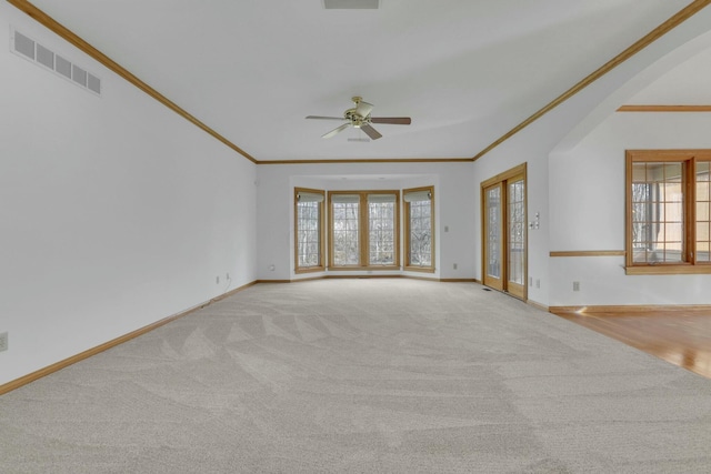 unfurnished living room with plenty of natural light, visible vents, and ornamental molding