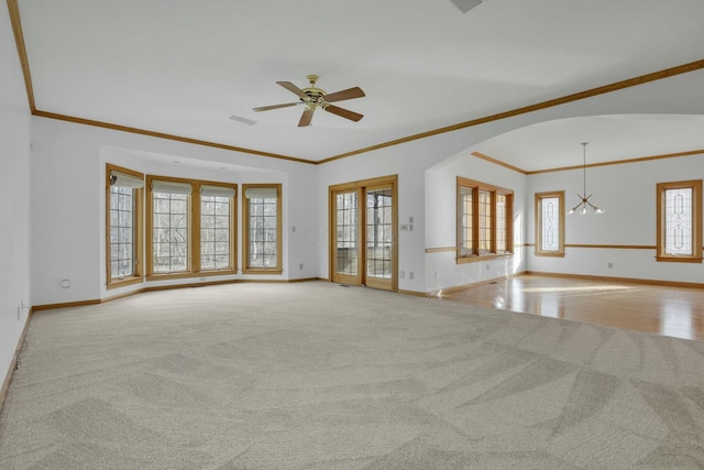 unfurnished living room featuring ceiling fan, baseboards, arched walkways, and carpet flooring