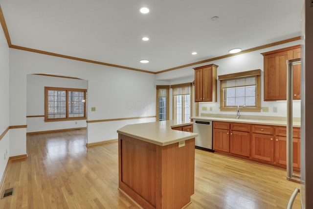 kitchen with light wood-style floors, light countertops, stainless steel dishwasher, a center island, and brown cabinetry