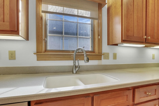 kitchen with light countertops, a sink, and brown cabinets