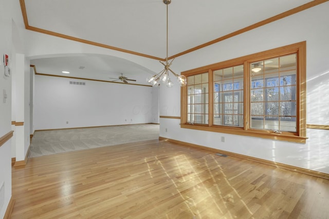 empty room featuring ornamental molding, arched walkways, visible vents, and wood finished floors