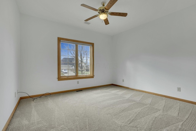 empty room with baseboards, a ceiling fan, visible vents, and light colored carpet